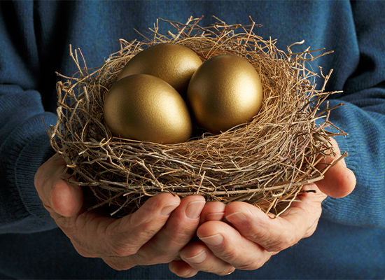 Senior Citizen holding three golden eggs in a birds nest